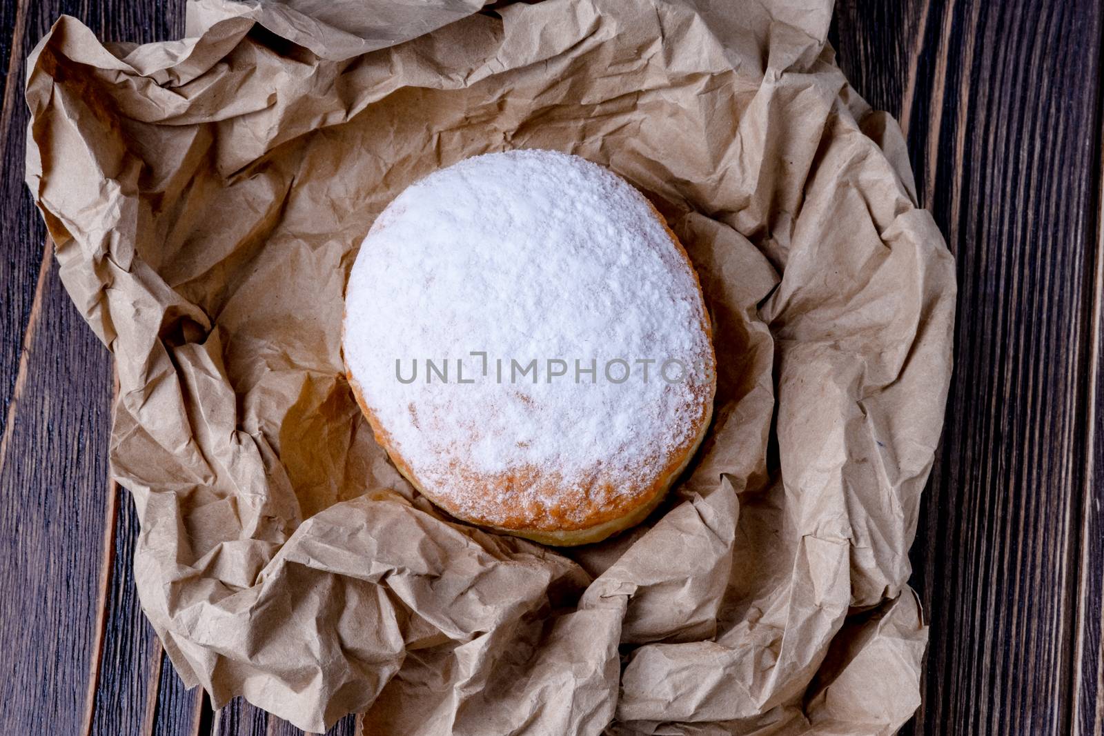 Berliner jelly filled doughnut with raspberry and redcurrant on wooden background.