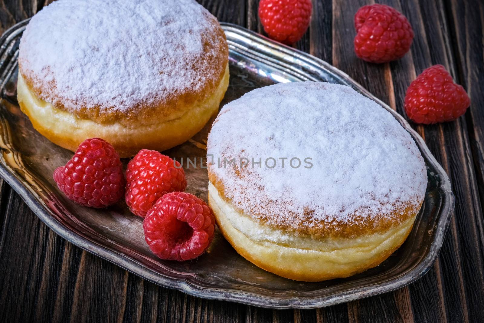 Berliner jelly filled doughnut with raspberry and redcurrant on wooden background.