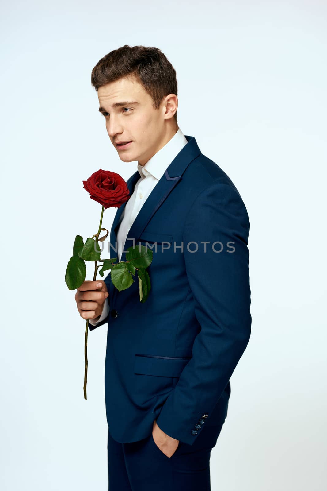 A man in a suit with a rose in his hands a gift date light background by SHOTPRIME
