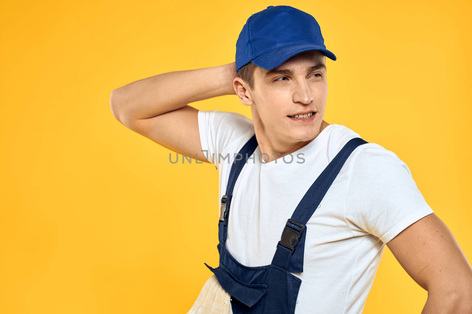 Working man in uniform of gloves rendering service yellow background. High quality photo