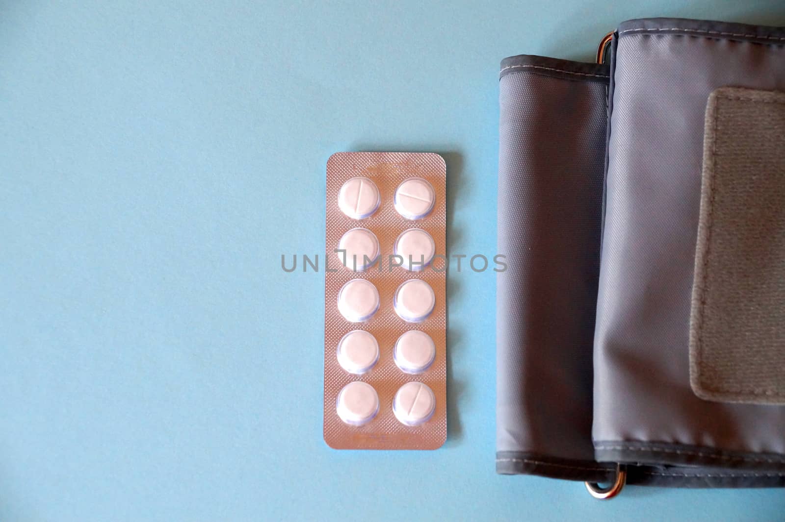 tonometer and pills on blue background, view from above.