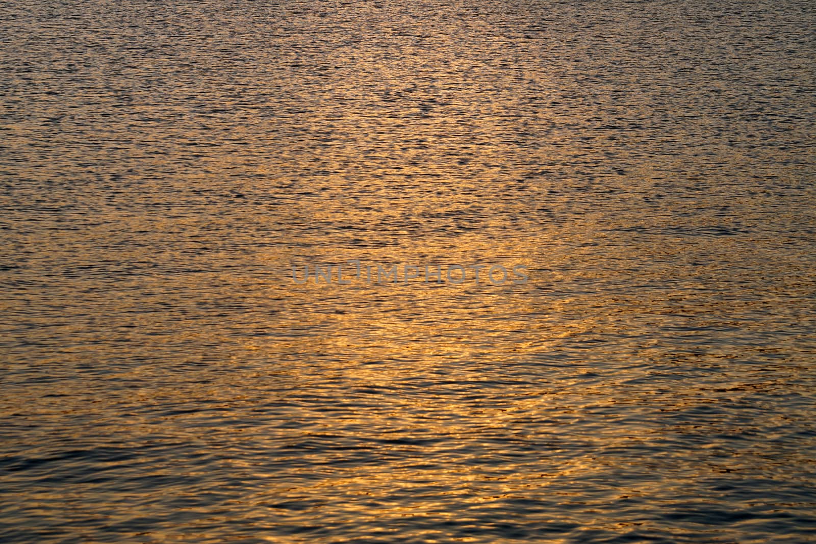 the setting sun is reflected in the dark sea water.