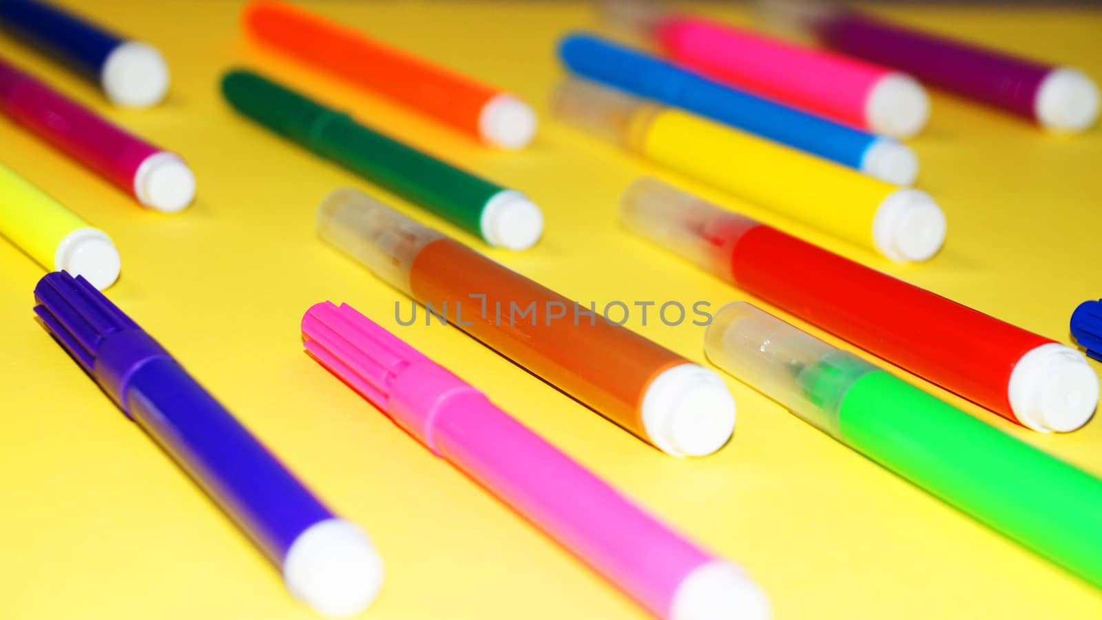 multicolored markers on a yellow background ckose-up by Annado