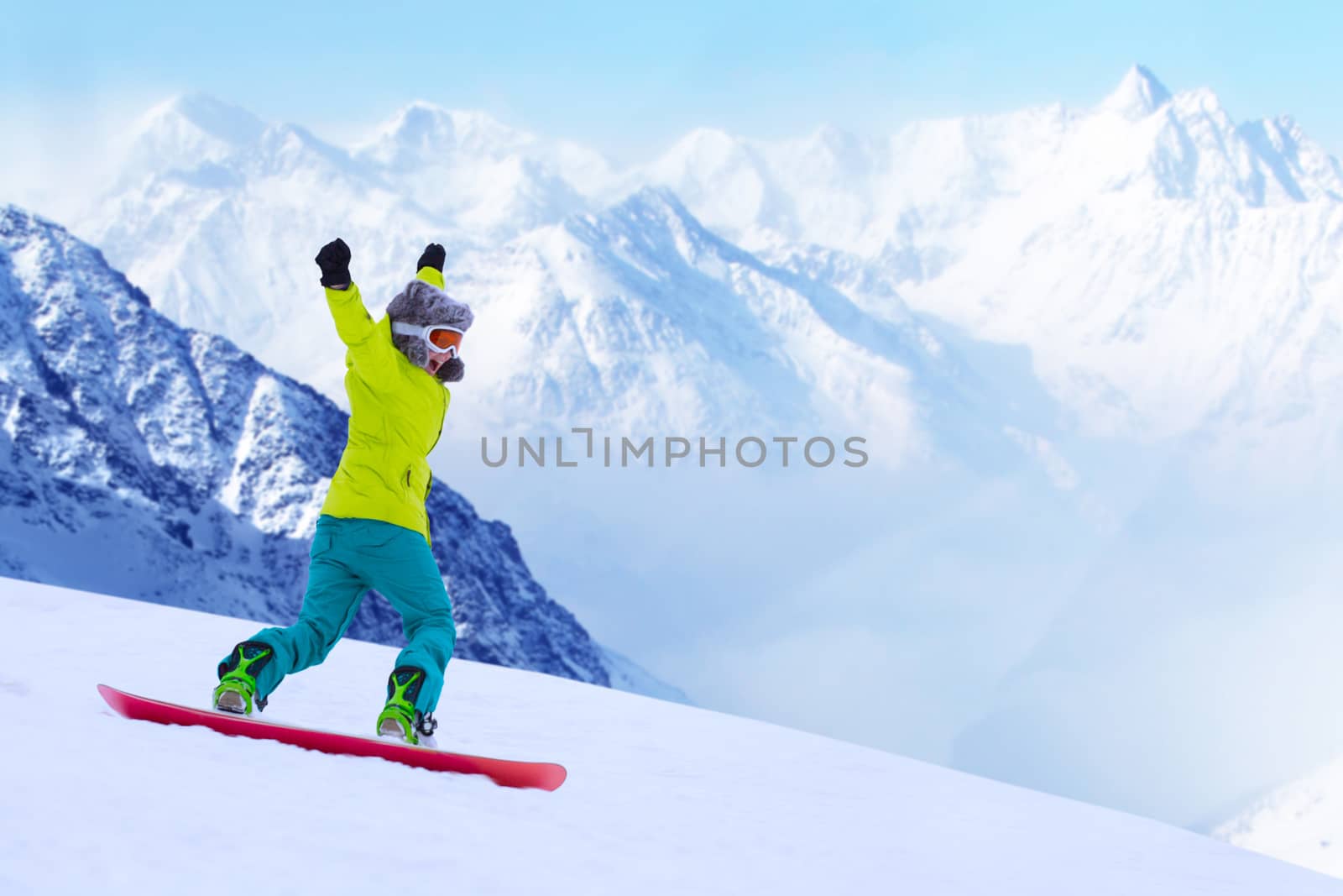 Girl snowboarder running down the slope in Alpine mountains. Winter sport and recreation, leisure outdoor activities. Image of excited screaming young woman enjoyment concept