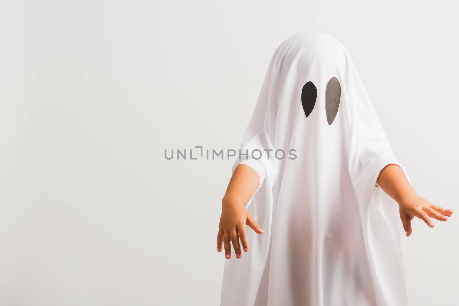 Funny Halloween Kid Concept, little cute child with white dressed costume halloween ghost scary, studio shot isolated on white background