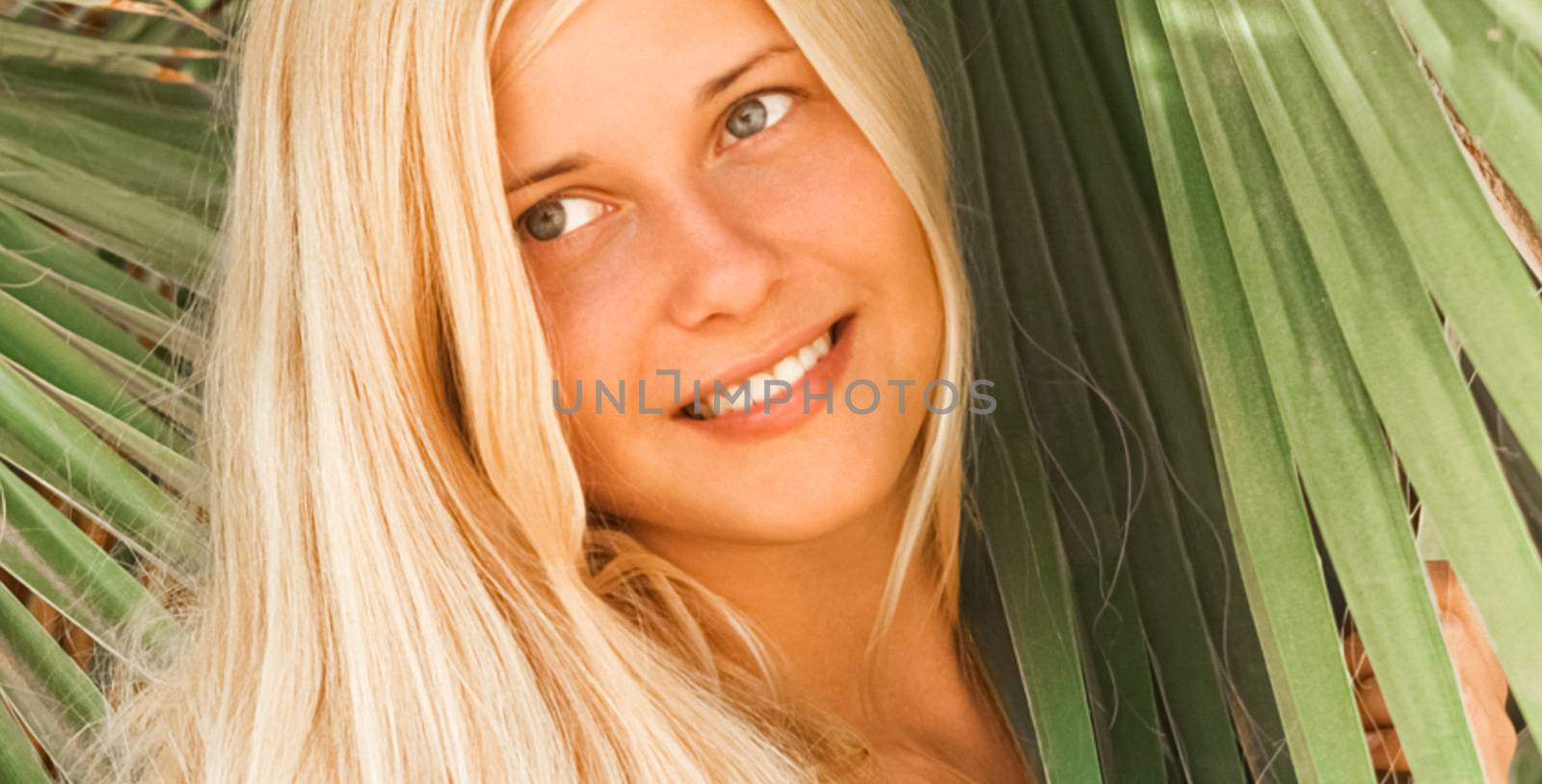 Woman with blond hair wearing bikini, posing near palm tree, beach lifestyle in summertime, holiday travel and leisure concept