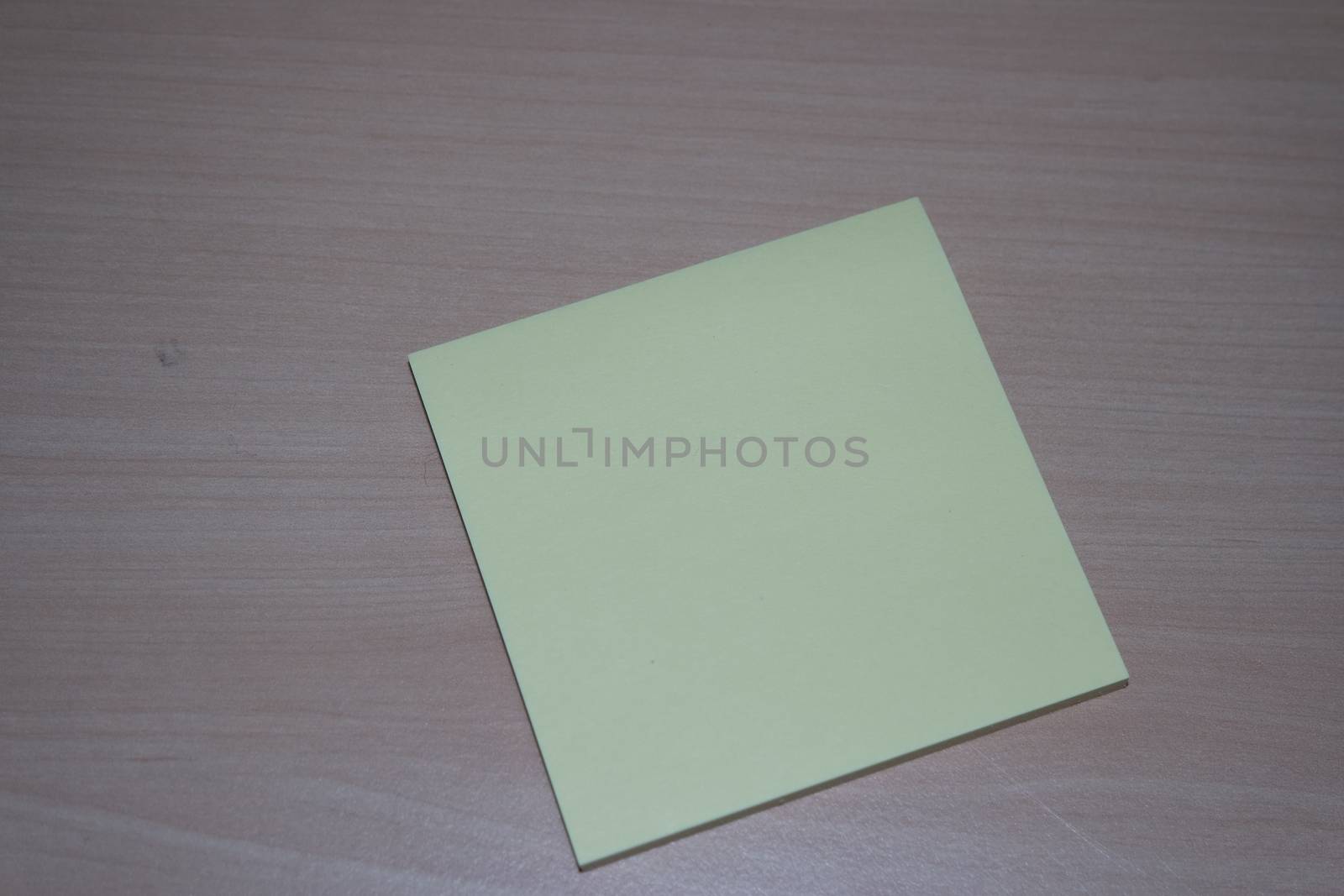 Yellow sticky note paper placed on a wooden table by Photochowk