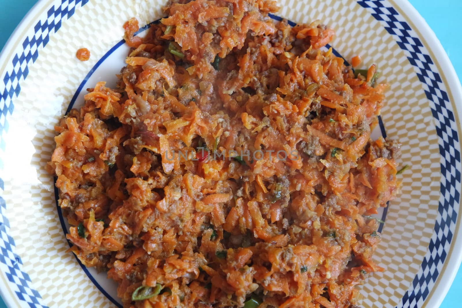 Top closeup view of a homemade dish made from carrot and vegetables served in a ceramic plate.