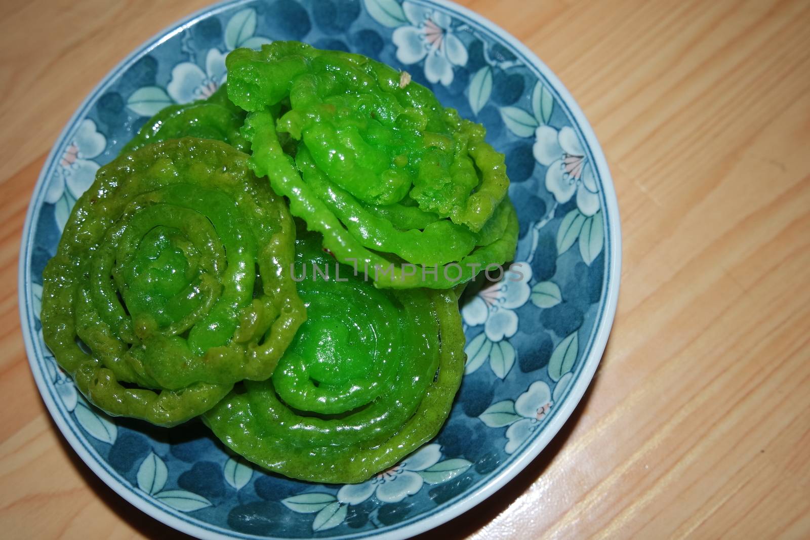 Crispy sweet Asian dessert green Jalebi cooked and served in ceramic plate, Indian sweet street food with juicy syrup, a closeup view.