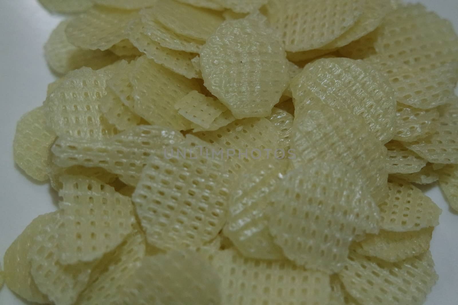 Closeup view with selective focus on dried chips as fast food for tea break. Potato chips with spices sprinkled on it. Fast food background for advertisements.