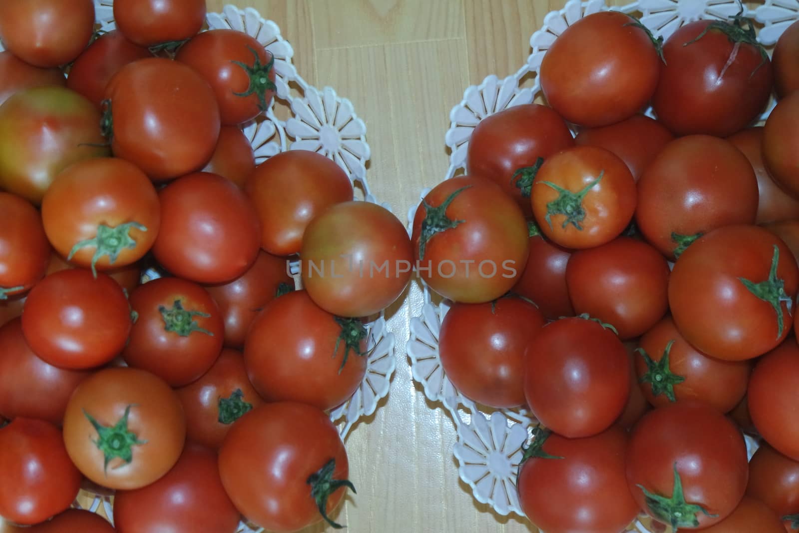 Close-up view of red tomatoes in white basket on a wooden floor in market for sale. A fruit background for text and advertisements