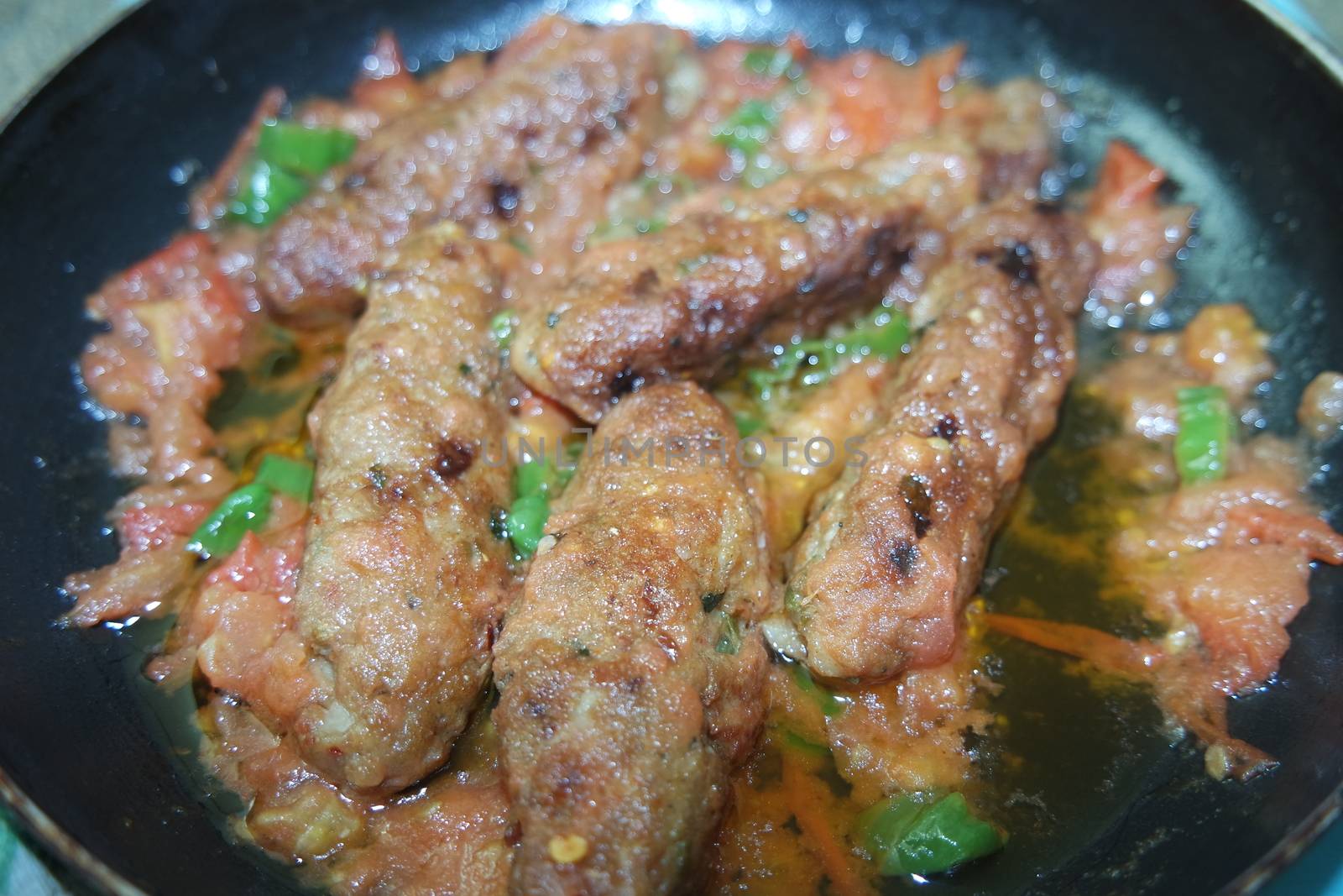 Closeup view of delicious spicy home made fried kebab with green mint leaves and green pepper sprinkled on it