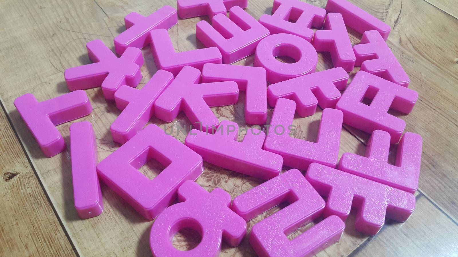Set of plastic alphabet letters placed on a wooden floor. Alphabet set is used for educating children to learn words and language