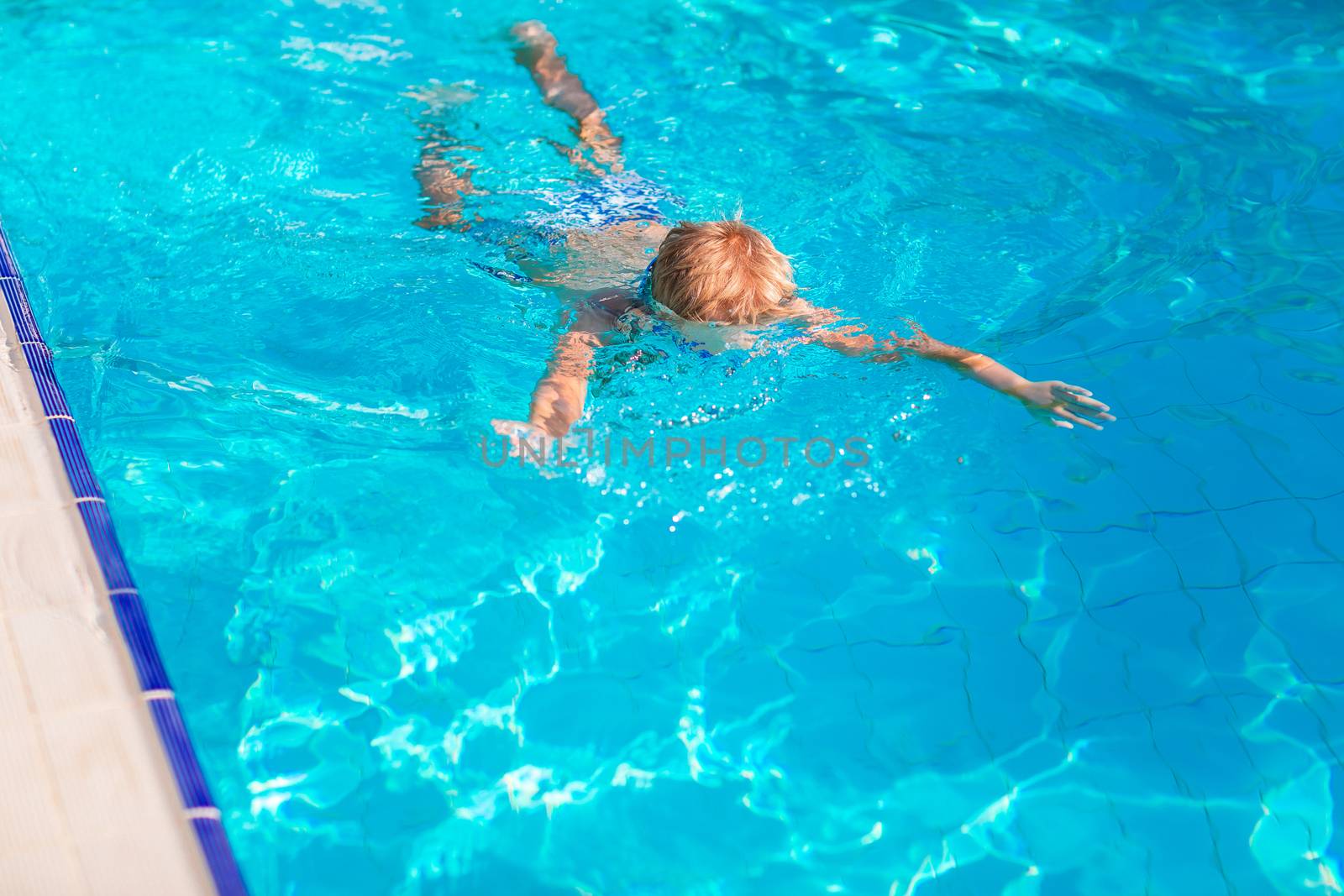 Cute happy little boy in goggles swimming and snorking in the swimming pool