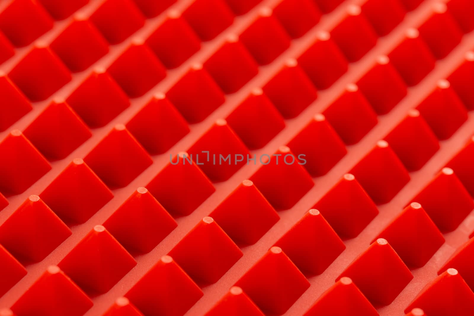 abstract red silicone pyramids array close-up background.