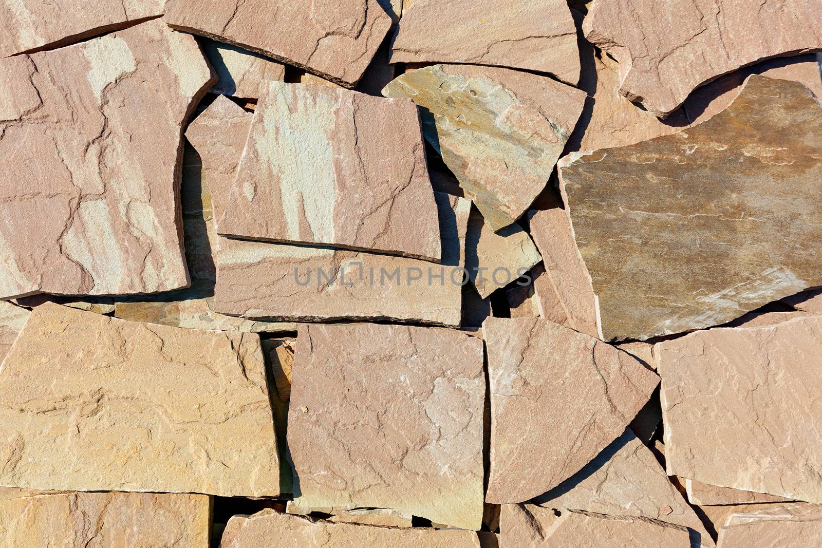 Texture and background of large slabs of brown sandstone in harsh sunlight.