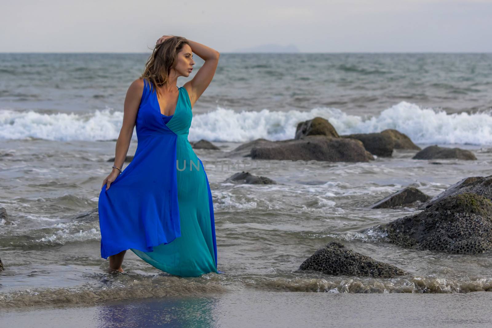 A beautiful brunette hispanic model posing outdoors on a beach at sunset
