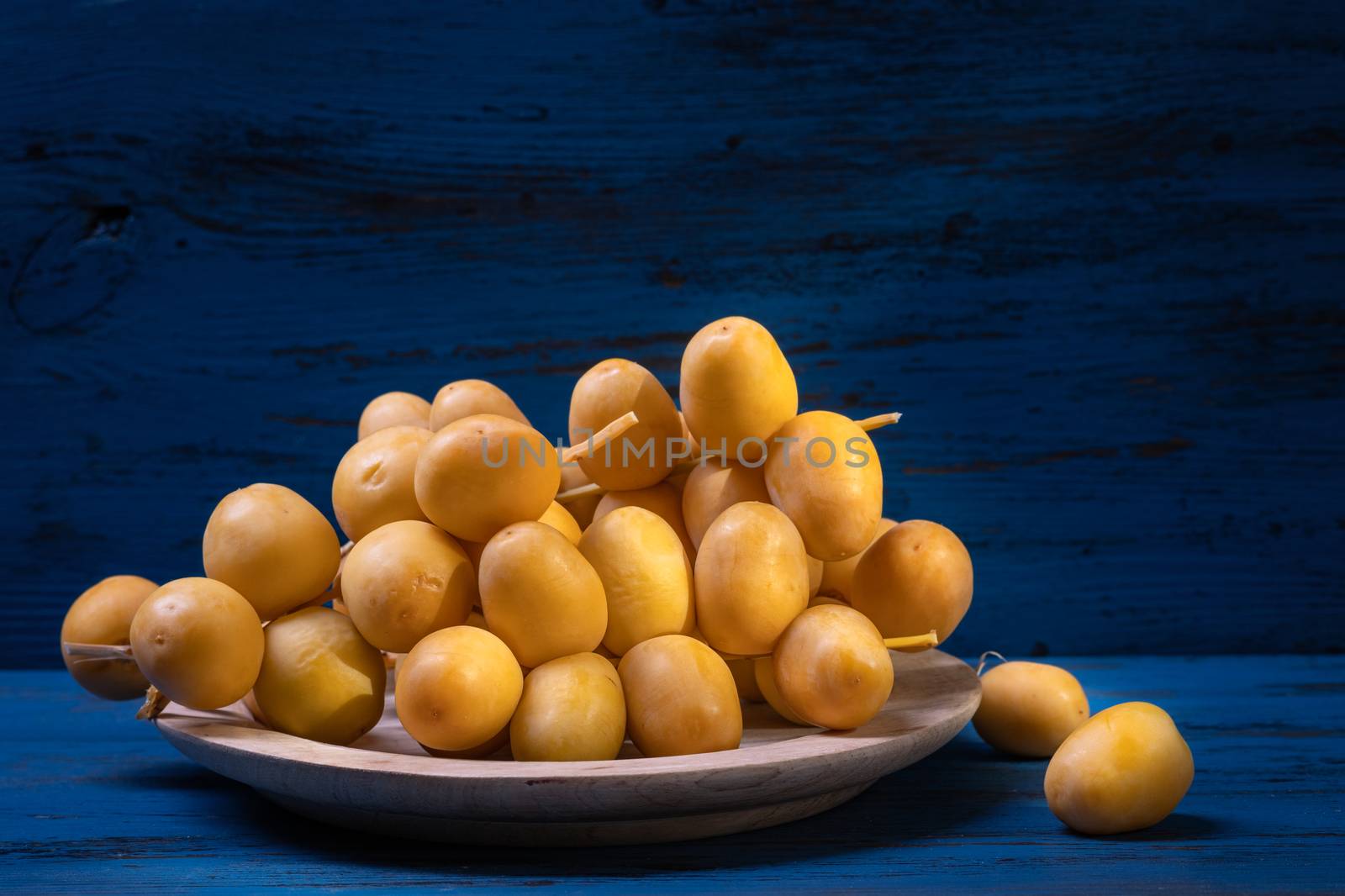 Dates or date palm in wood bowl on wooden background. Healthy fruit.