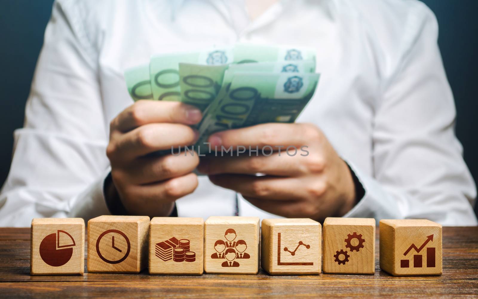 A man is counting money and blocks with business attributes. Good business model. Profitability. The rules for successful investment. High performance, great work. Company management
