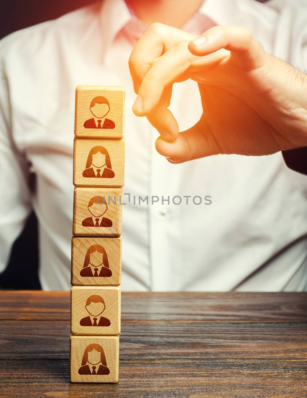 Man knocks down a tower of blocks with employees. Mass layoffs, closing a business company. Dismissal workers. Elimination of competitors, repression. Poor leadership. Disbandment of team collective.