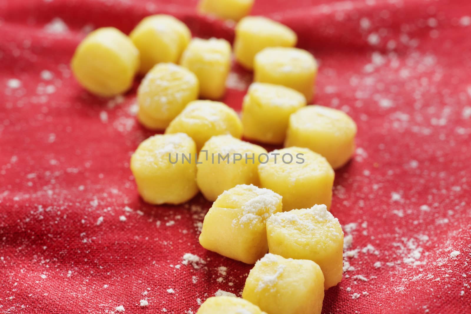 Tasty thick  and small handmade gnocchi -dough dumplings - on red cloth ,it’s a variety of pasta made with semolina wheat flour and egg