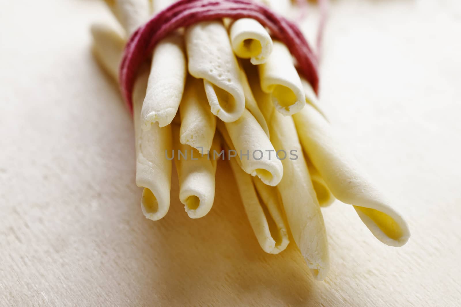 Italian pasta called maccheroni calabresi on wooden background ,long and thick pasta made with durum wheat semolina and water ,tipical pasta of Calabrian tradition