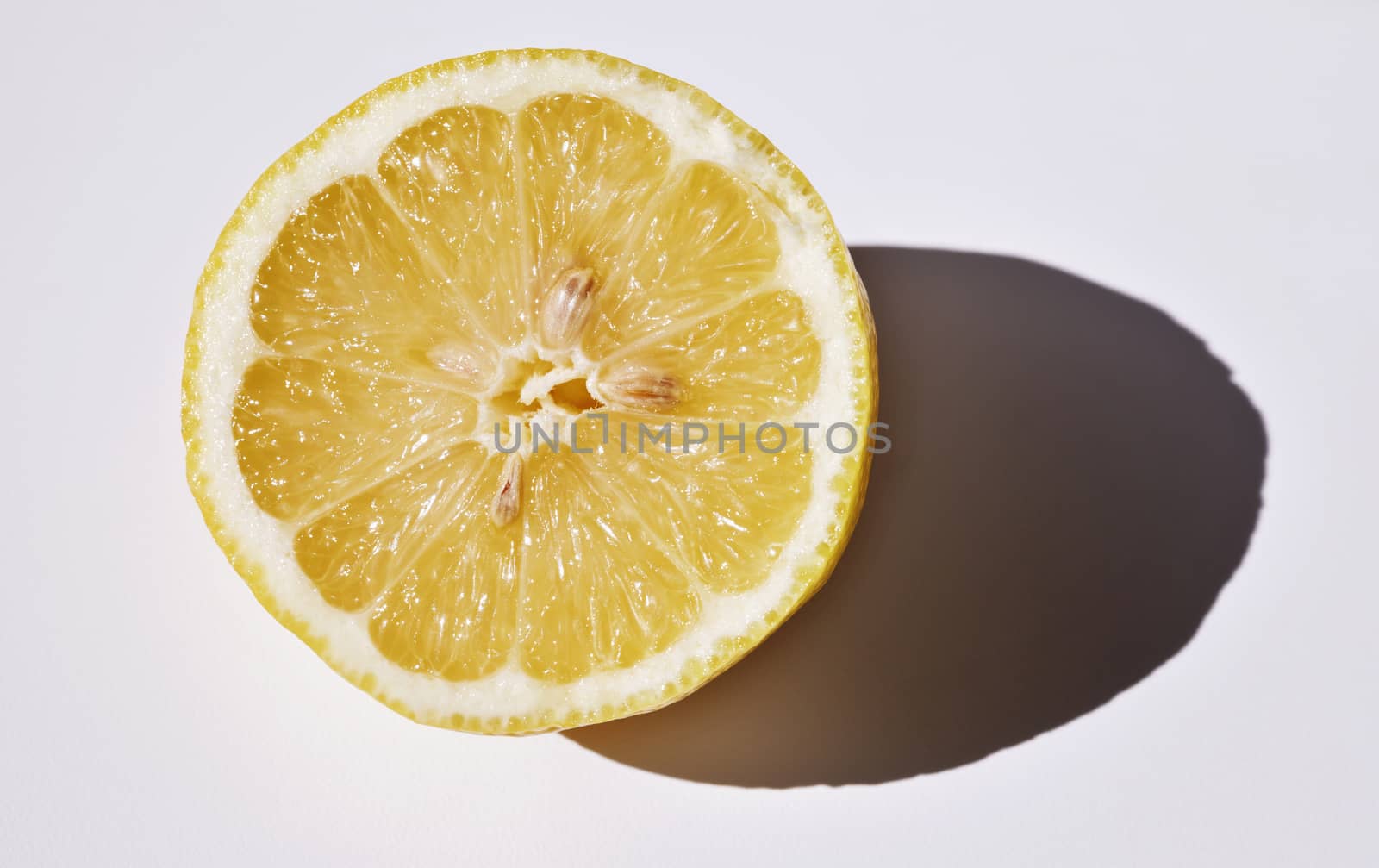 Beautiful slice of lemon with dark shadow on white background , studio shot 