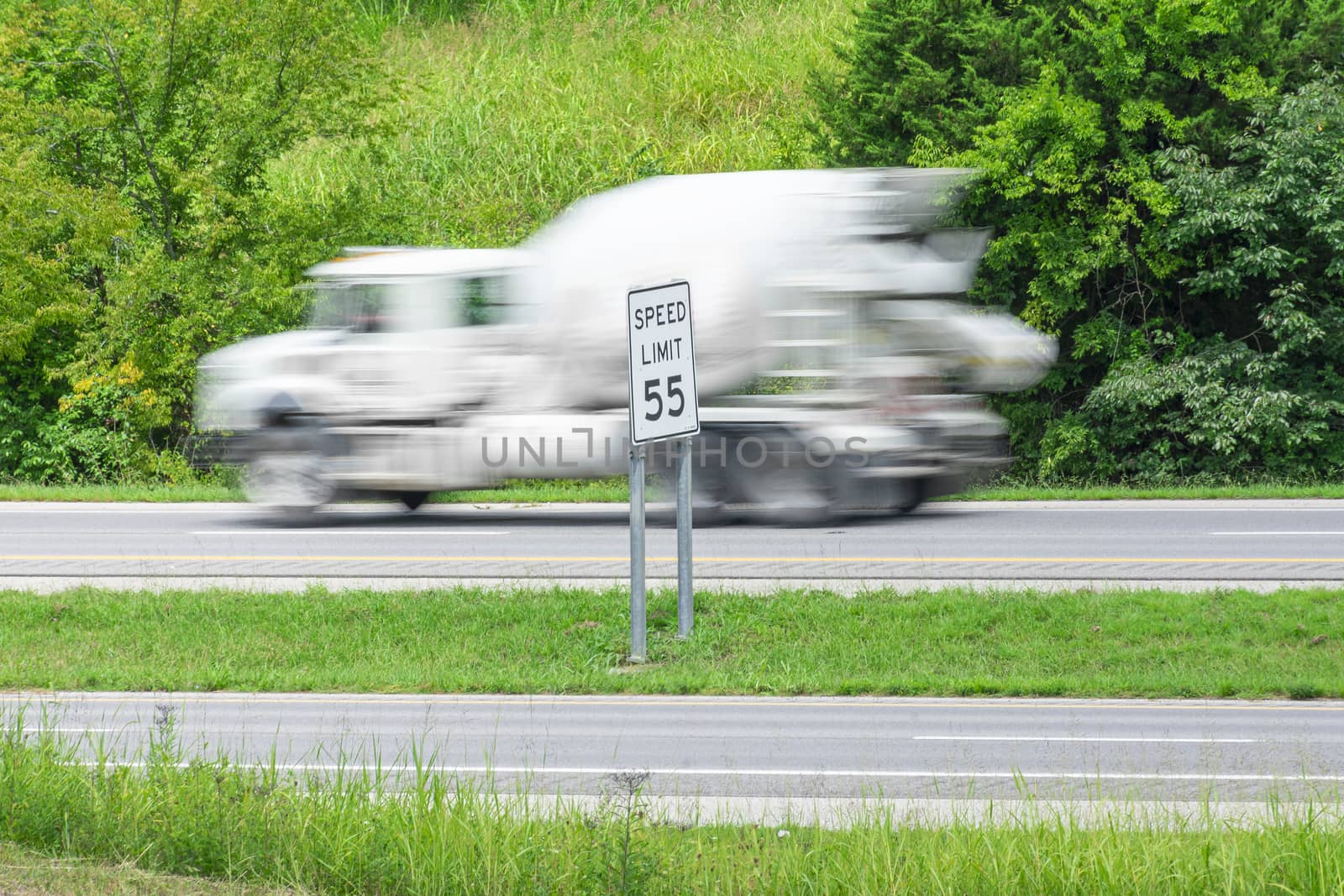 Speeding Concrete Truck Races Past Speed Limit Sign by stockbuster1
