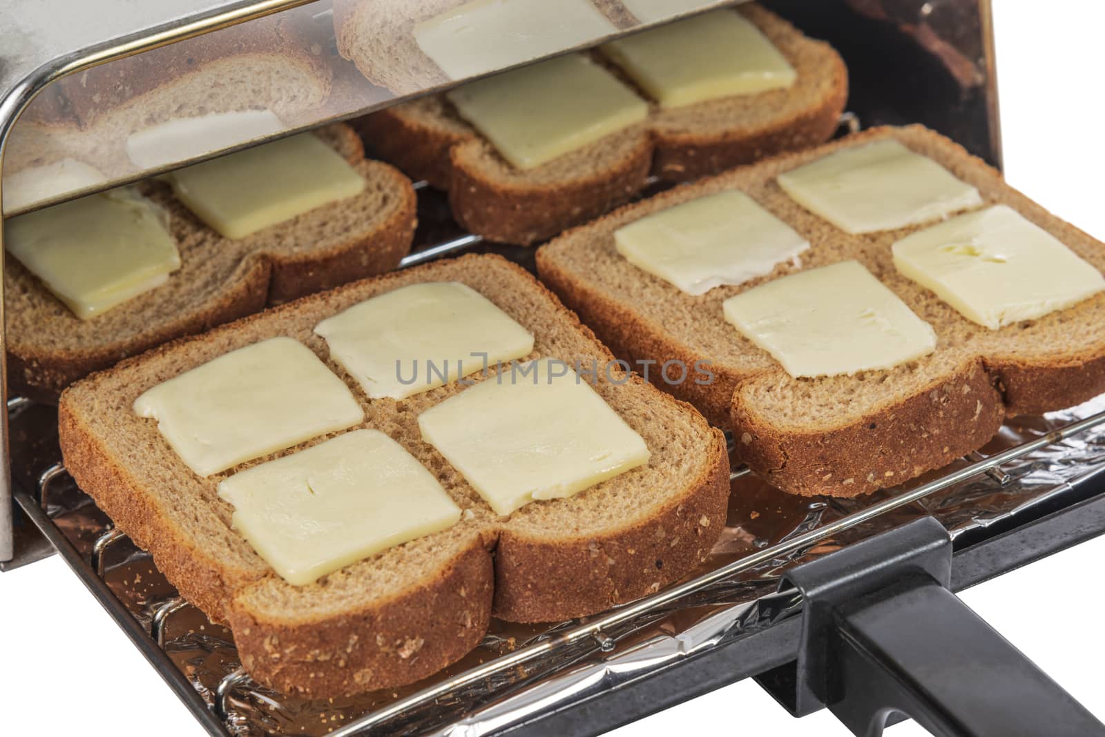 Horizontal shot of four pieces of buttered wheat bread about to be pushed into the toaster and toasted.