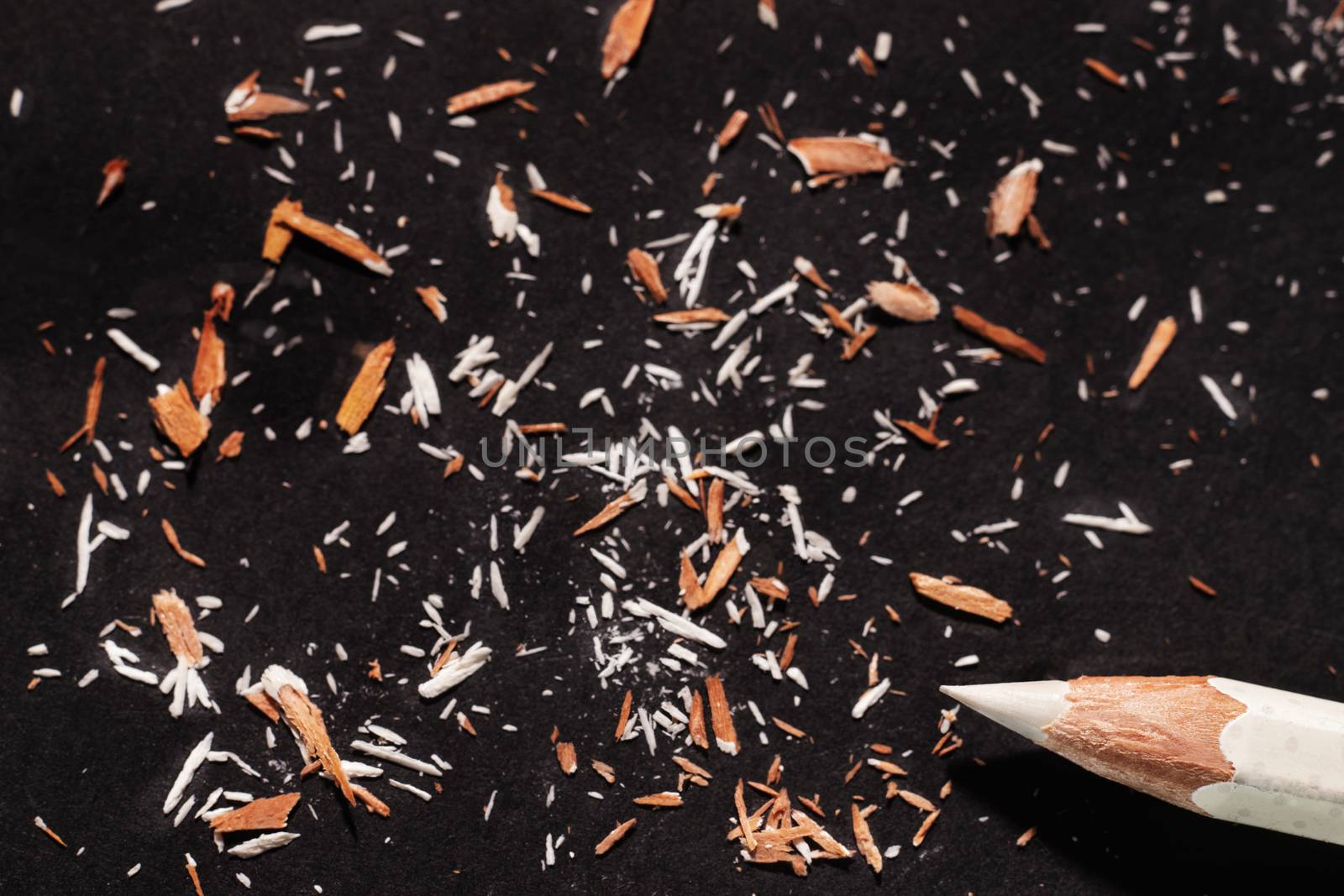  Sharpened white  wooden pencil on black background , beautiful pencil shavings all around 