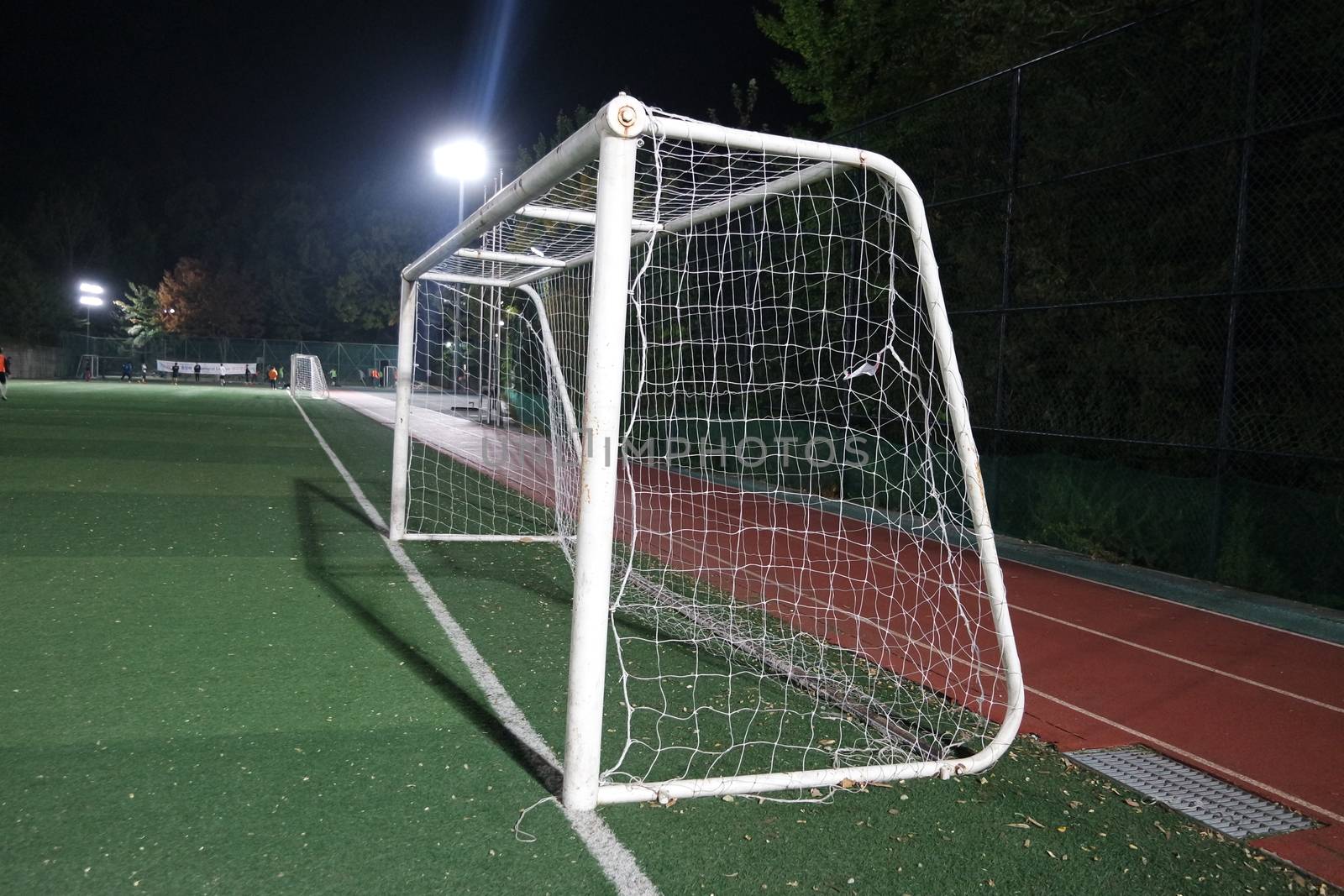 Night view of a soccer goal net under flood lights. Closeup view of goal net in a soccer playground