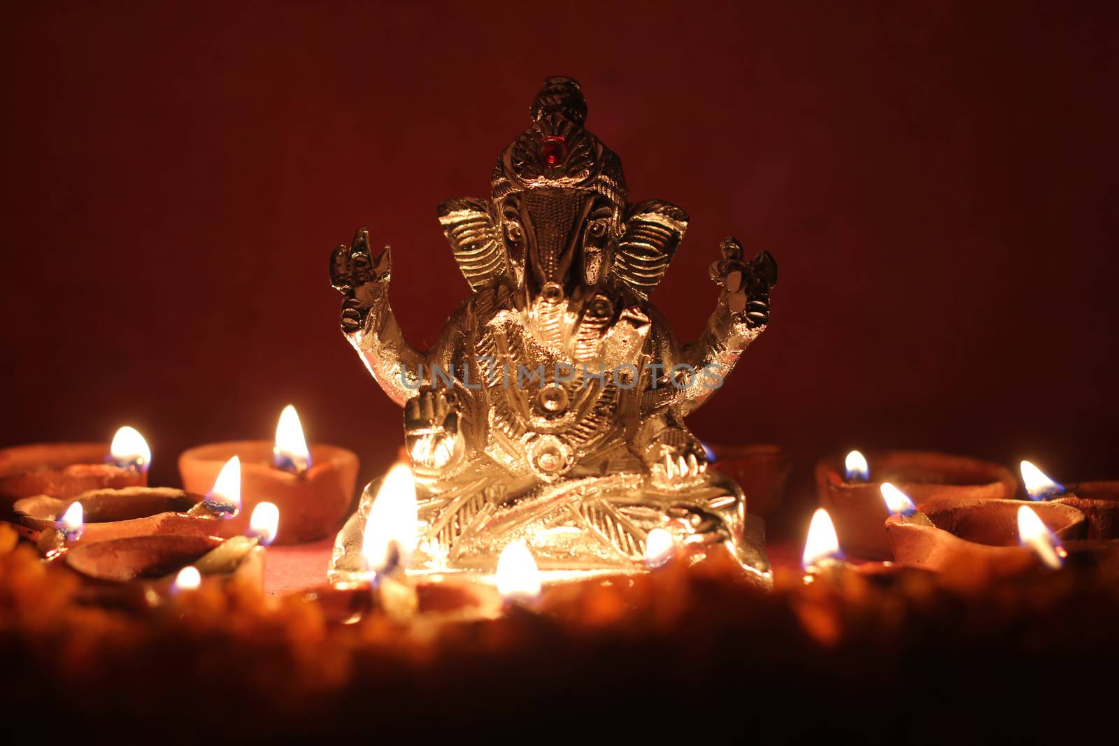 lord ganesha statue with oil lamp illuminated around