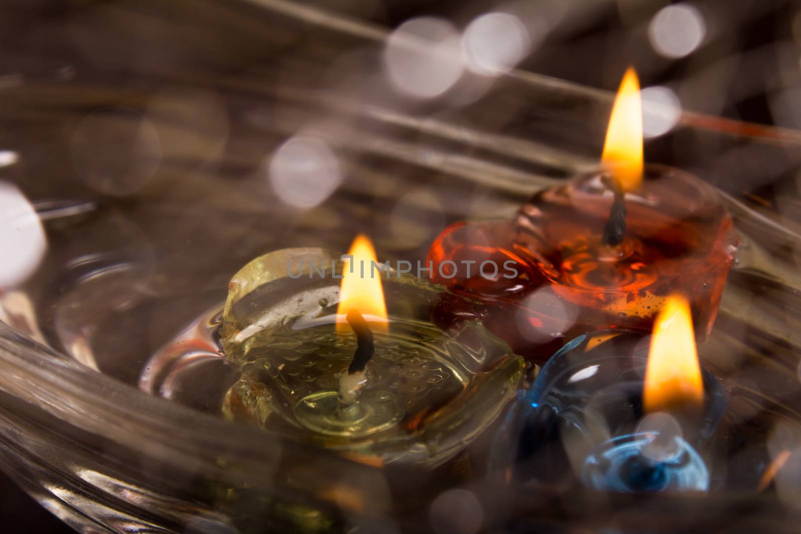 floating burning candles on water with bokeh