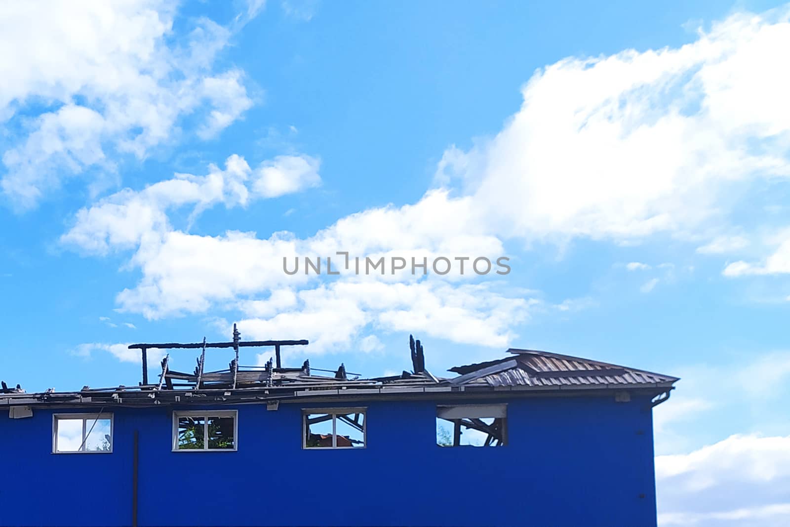 modern frame house with broken roof against cloudy sky background.