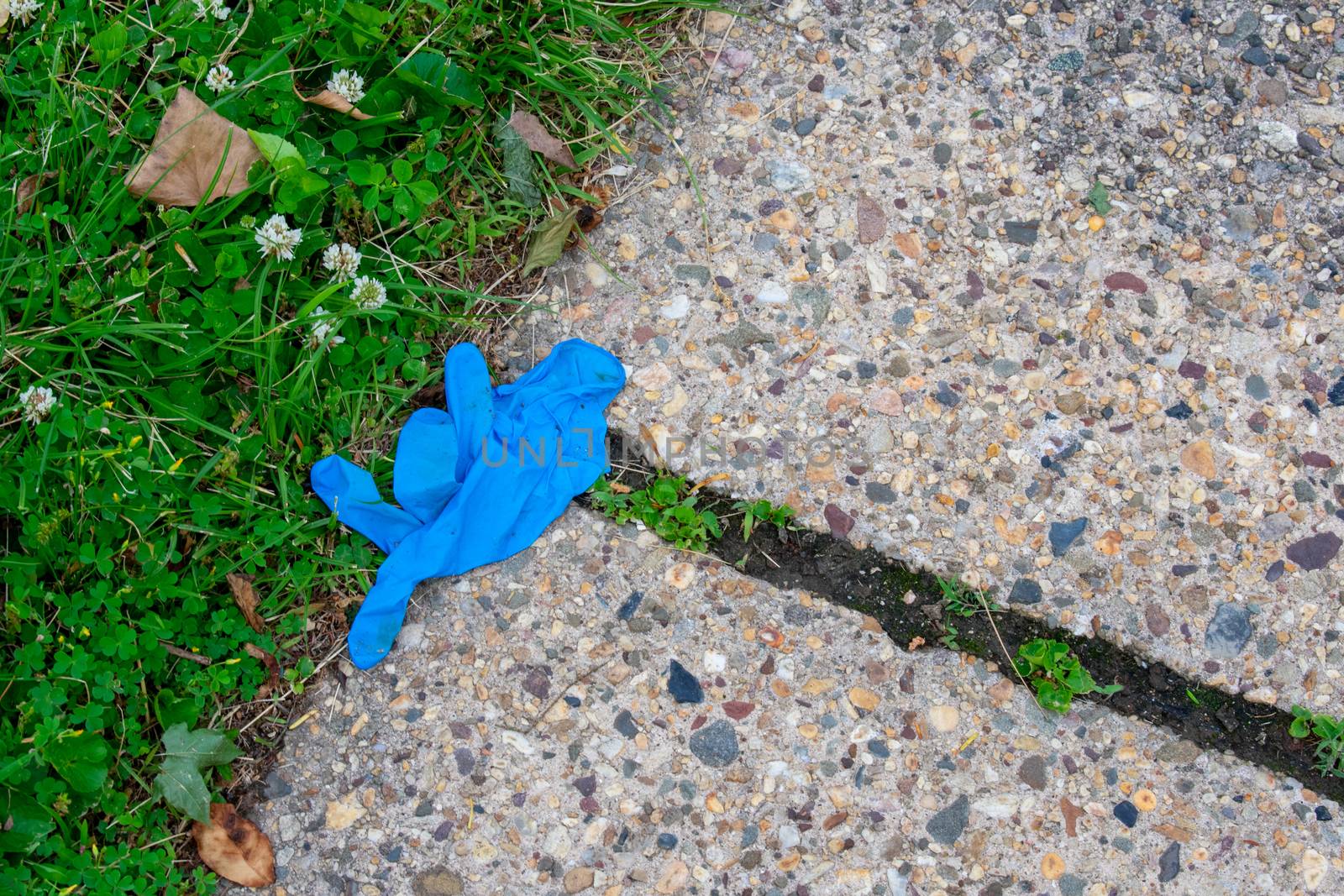 An Old Blue Medical Glove on the Sidewalk for Protection Against COVID-19