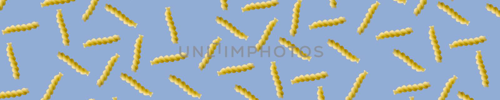 Fusilli pasta random flat lay on blue background without shadow. can be used as raw pasta background, poster, banner not pattern