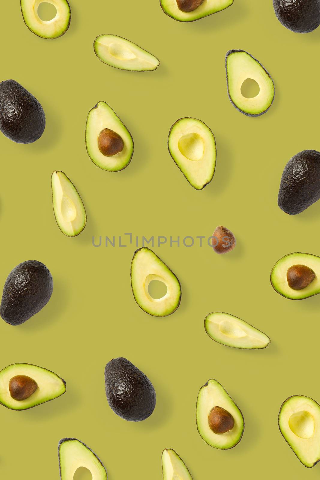 Avocado. Background made from isolated Avocado pieces on olive color background. Flat lay of fresh ripe avocados and avacado pieces. by PhotoTime