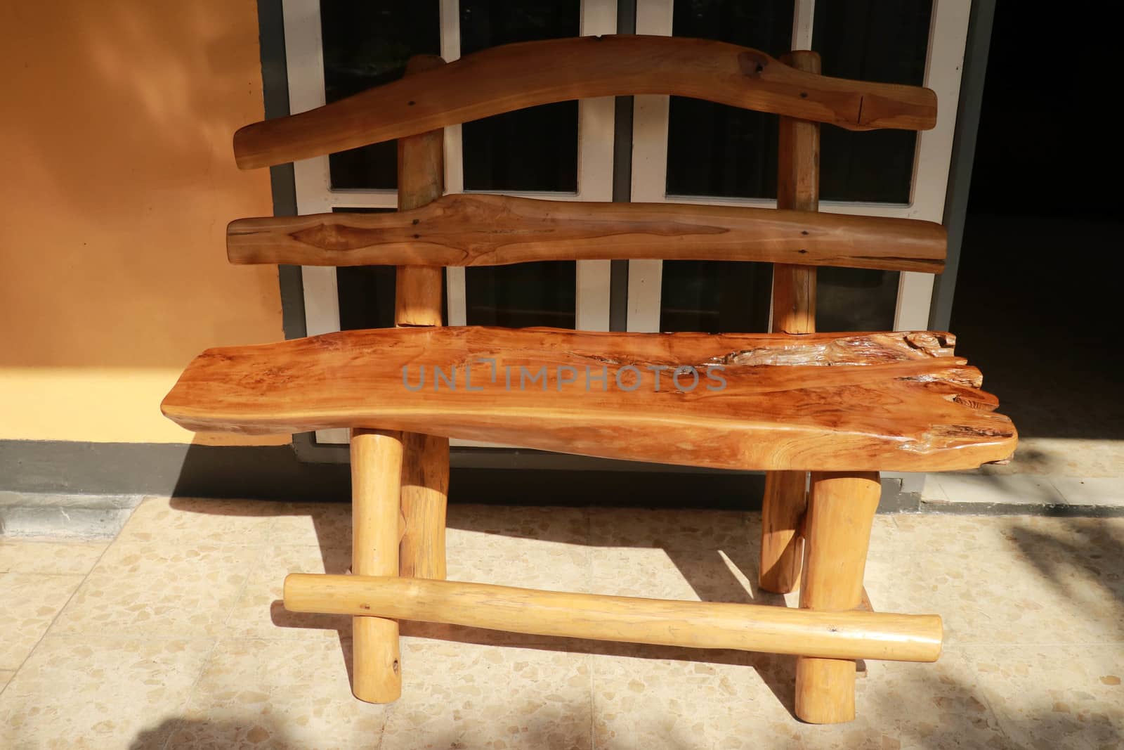 Bench. Wooden. of rough planks and logs. rustic bench of ecological materials. Close up of a vintage wooden bench in front of a white glass door.