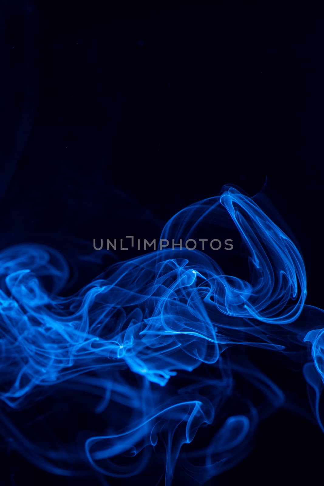 Conceptual image of blue color smoke isolated on dark black back by ROMIXIMAGE
