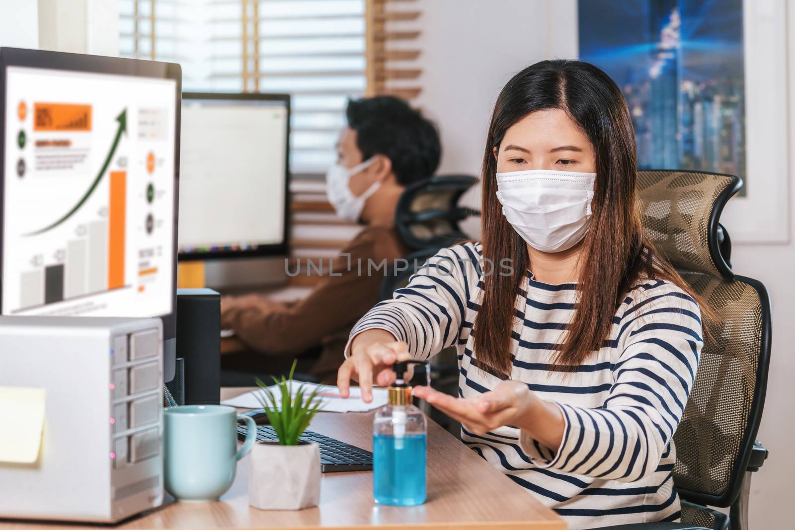 Asian woman worker using hand sanitizer for cleaning her hand when working  with computer in Home office when Covid-19 pandemic, Coronavirus outbreak,education and Social distancing,new normal concept