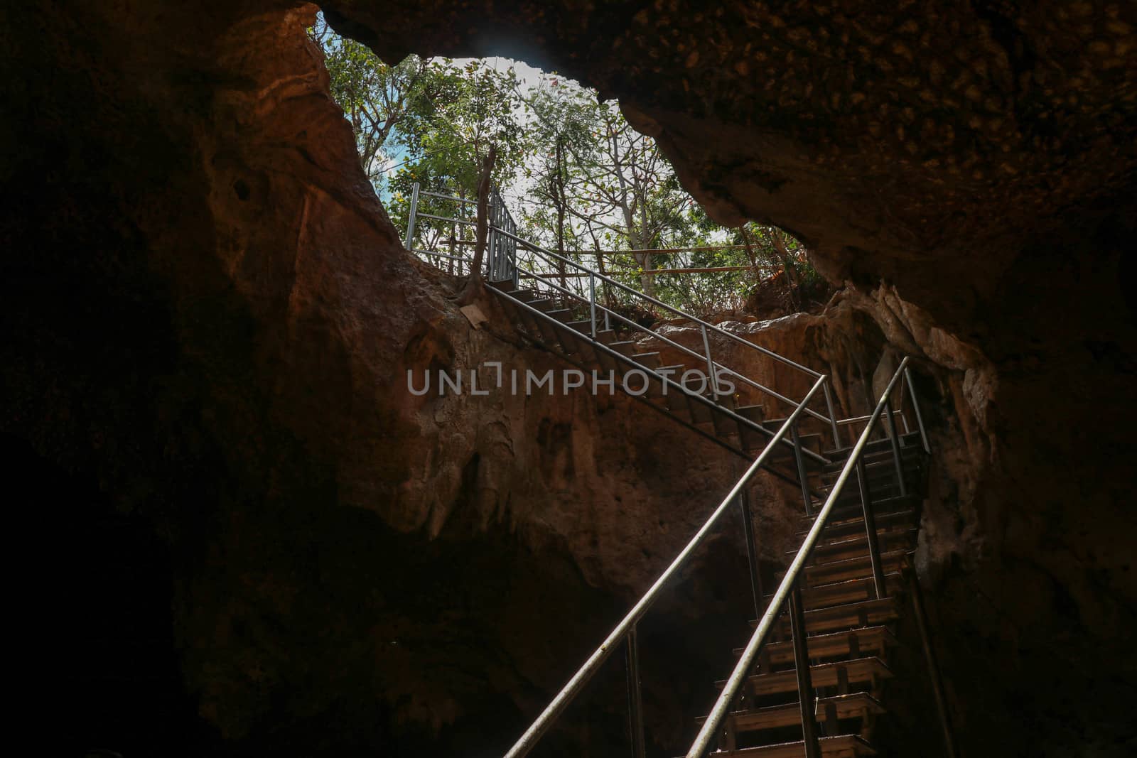 Stainless steel staircase in the cave. Stainless steel staircase to GOA BANGKANG PRABU cave, a bat cave on Lombok island, Indonesia. Bottom view of the blue sky.