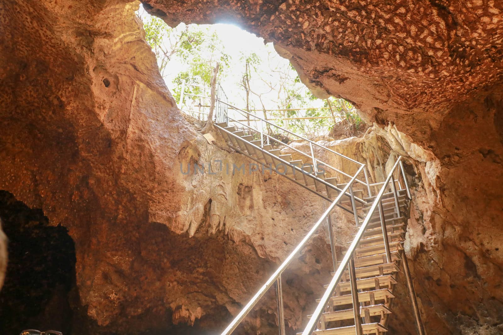 Stainless steel staircase in the cave. Stainless steel staircase to GOA BANGKANG PRABU cave, a bat cave on Lombok island, Indonesia. Bottom view of the blue sky.