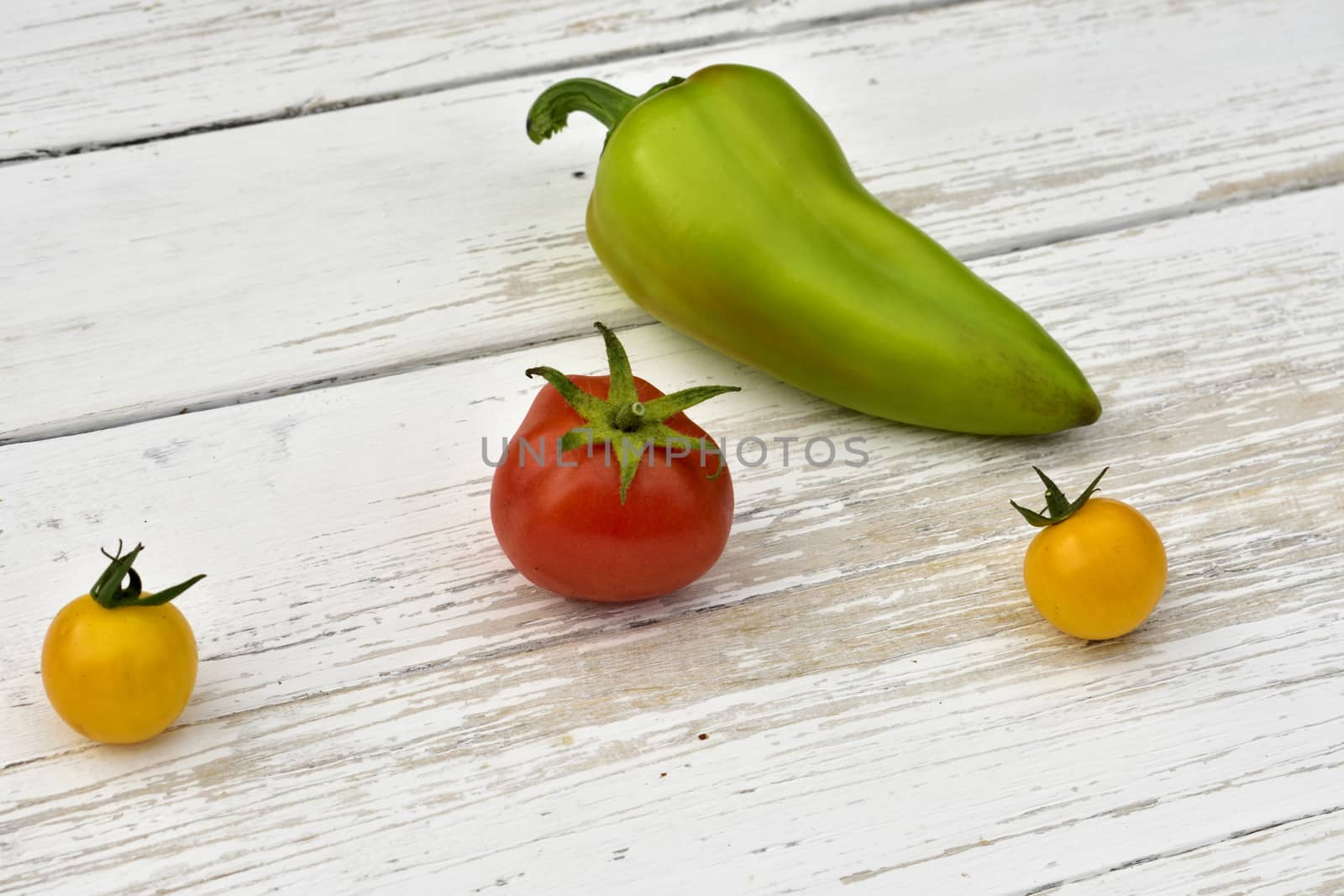 red tomato, two yellow small tomatoes and bell pepper pod