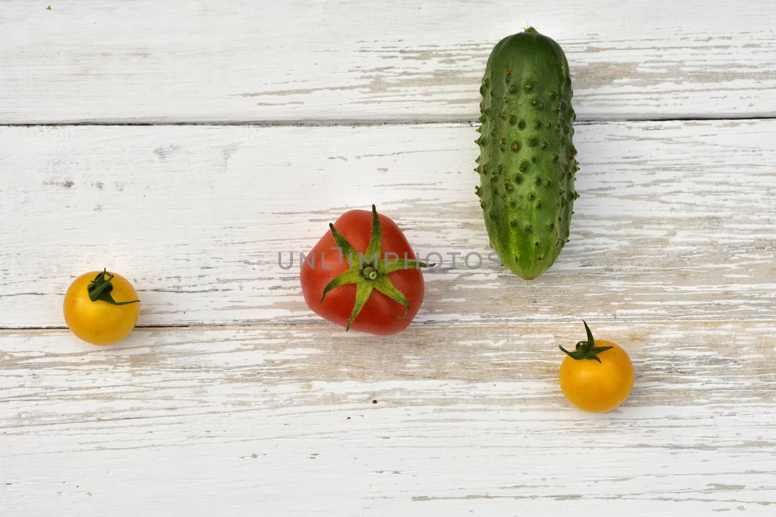 red tomato, two yellow small tomatoes and a cucumber, top view