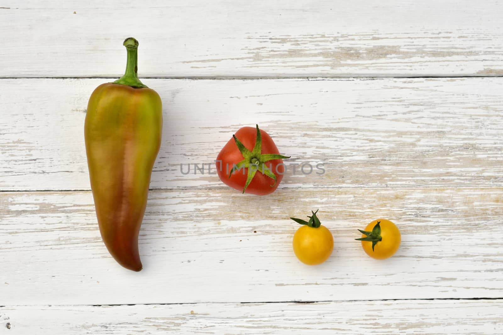 red tomato, two yellow small tomatoes and bell pepper pod, top view