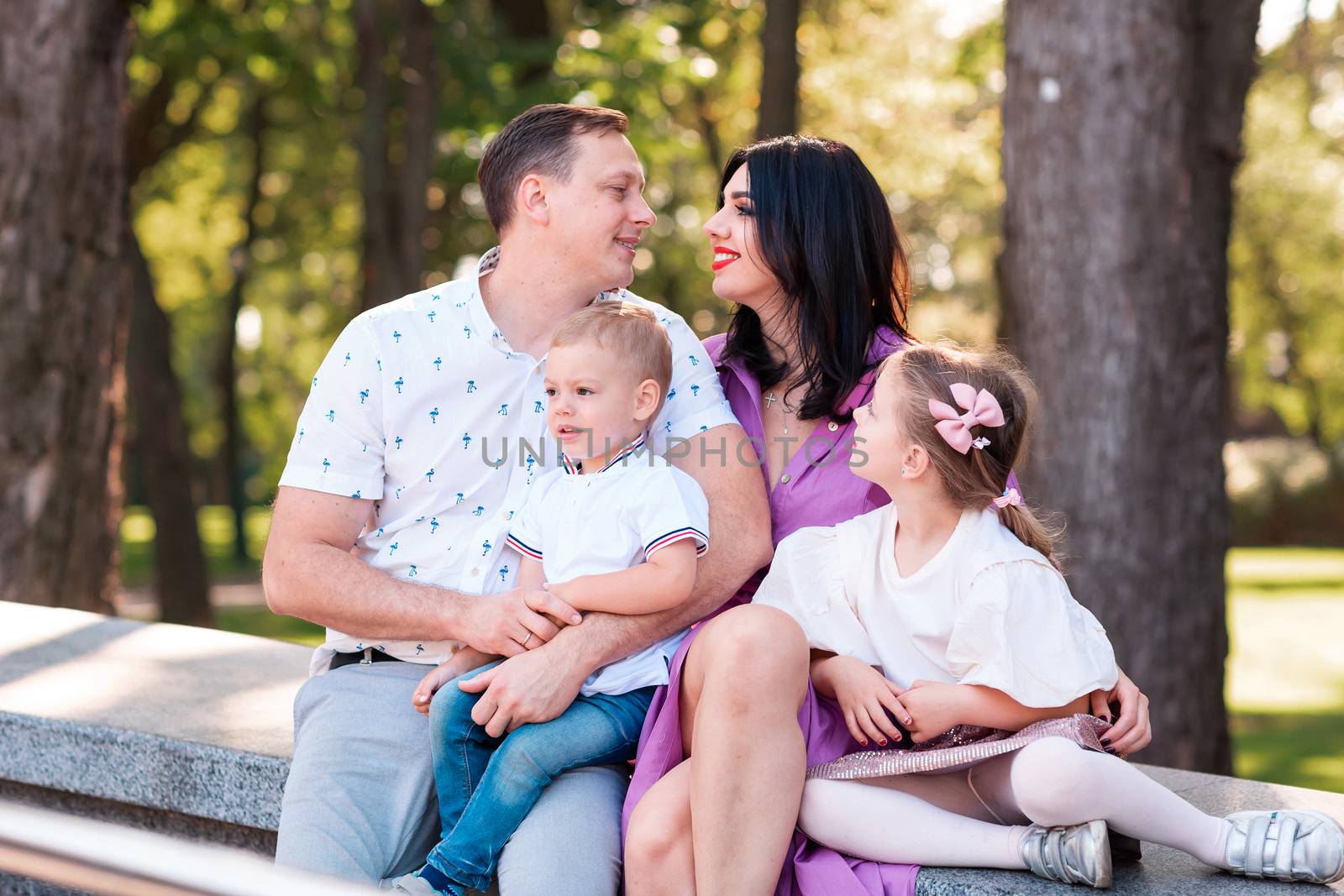 Happy young family with two kids walking in the park. Happy parenting concept