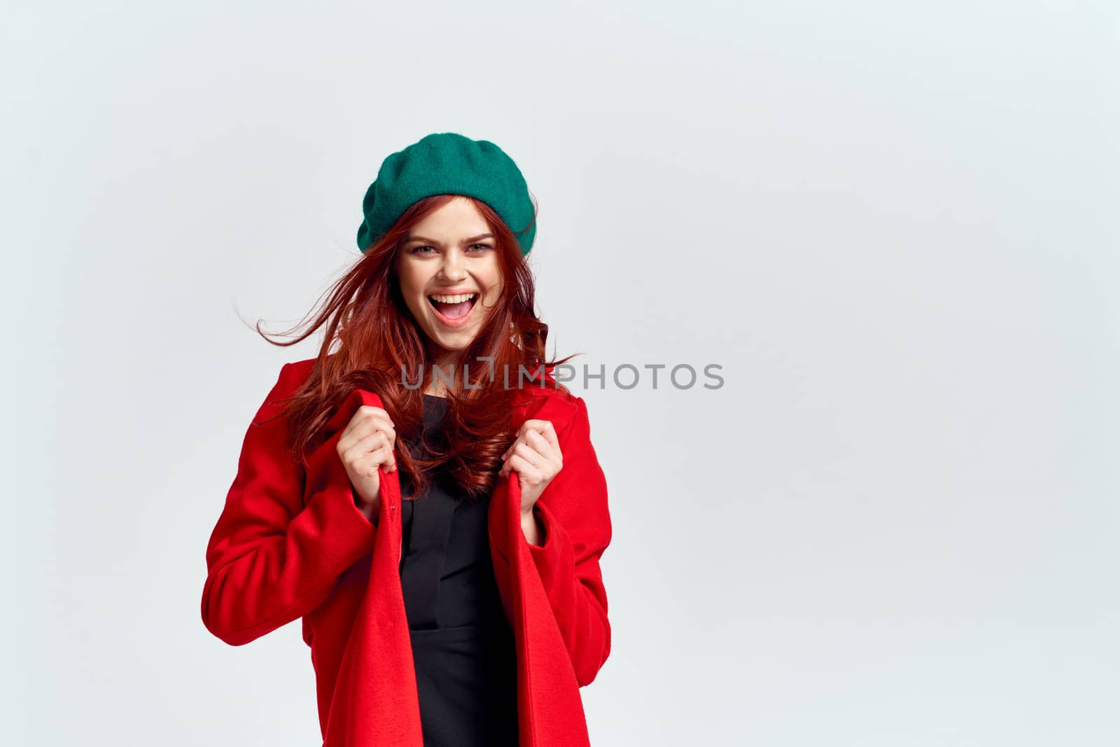 Portrait of a woman in a red coat and in a green hat dark clothes light background model cropped view by SHOTPRIME