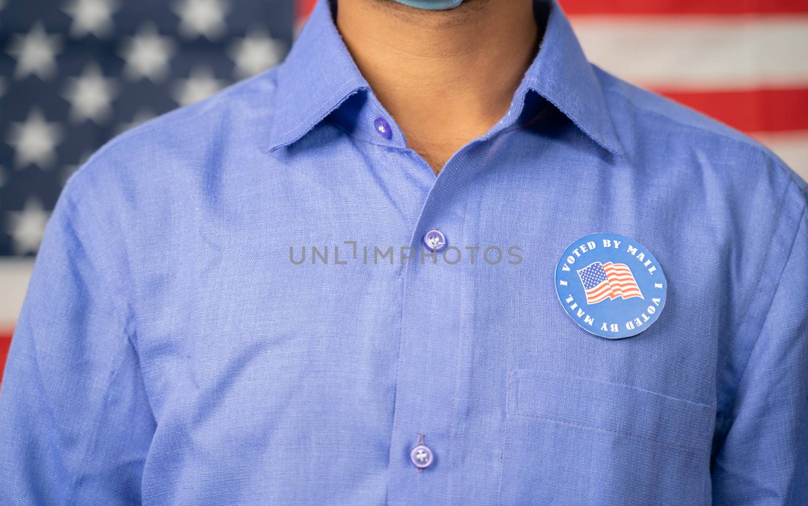 Unrecognizable Man Pasted I voted by mail sticker on his sticker with US flag as background - Concept of US election, mail-in voting or vote by mail.