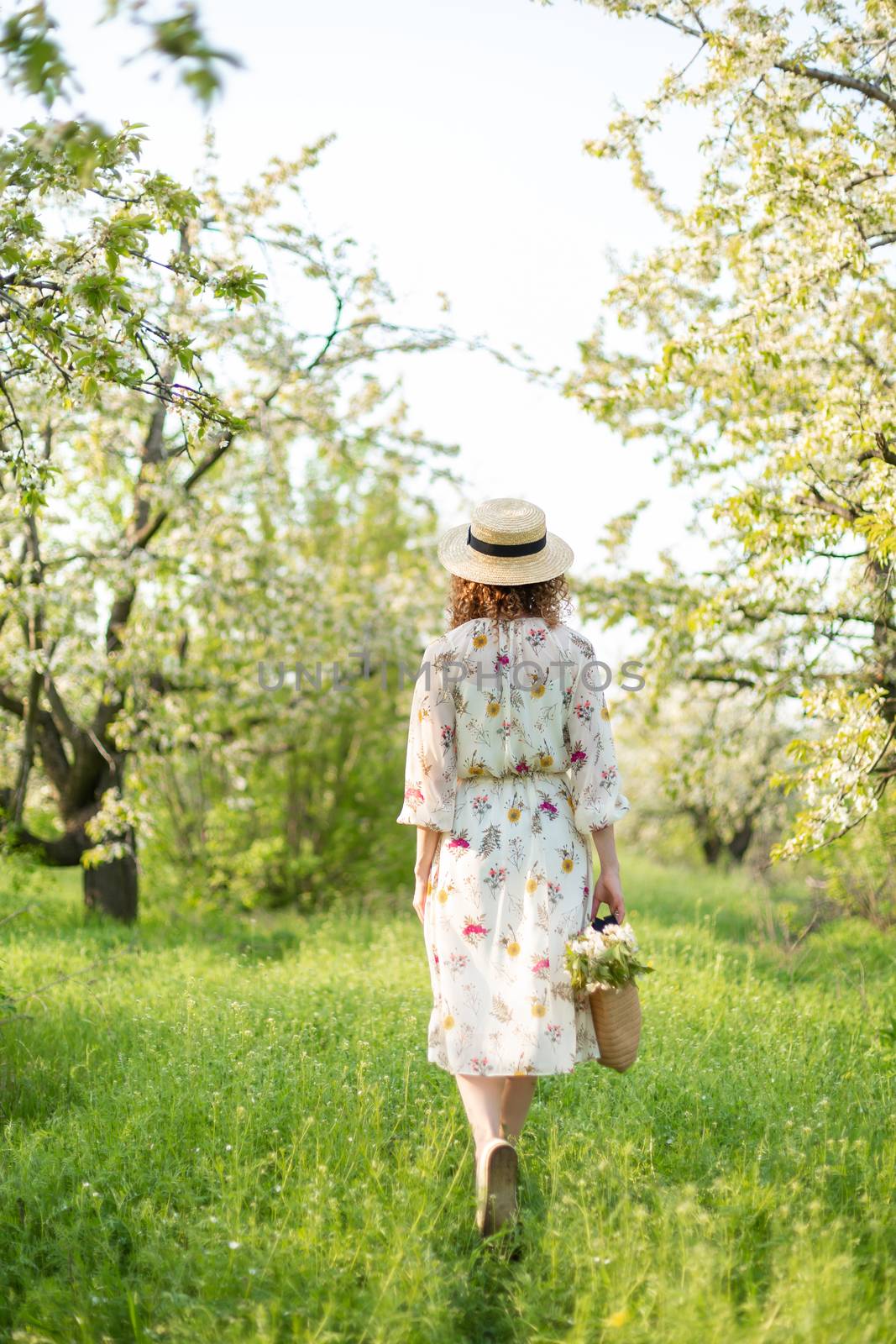 A gorgeous girl walks in a flowering spring garden. The concept of unity of man with nature.