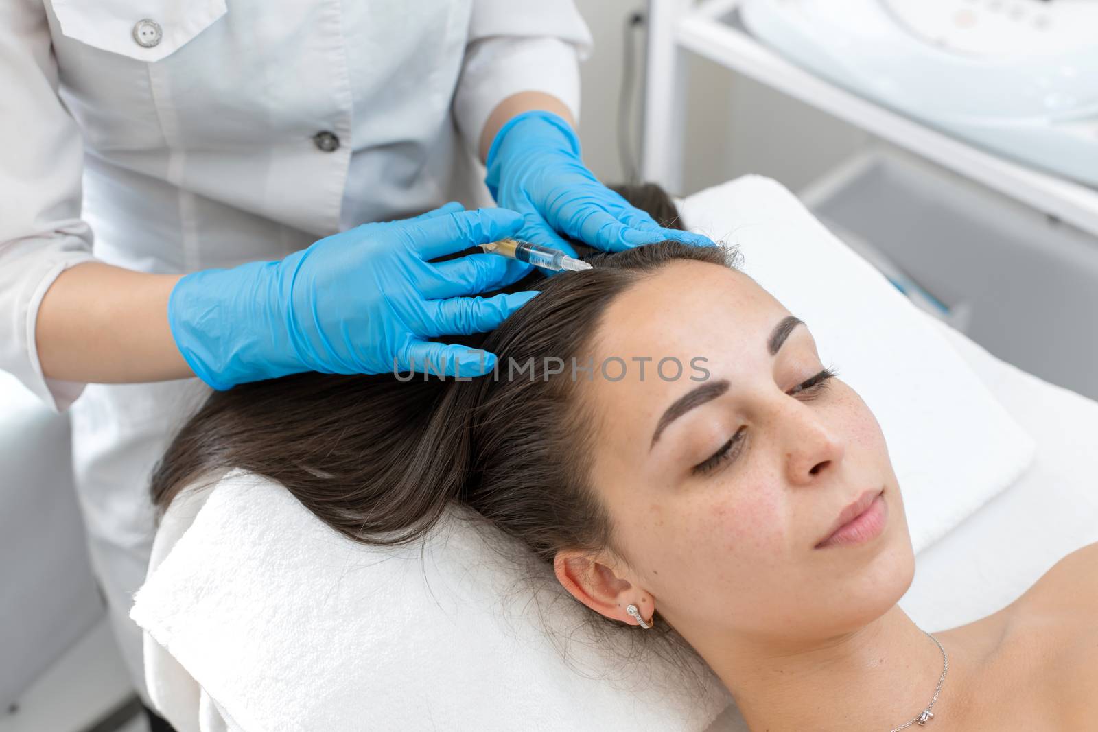 Close-up, the beautician makes injections of vitamins into the scalp for strengthening the hair